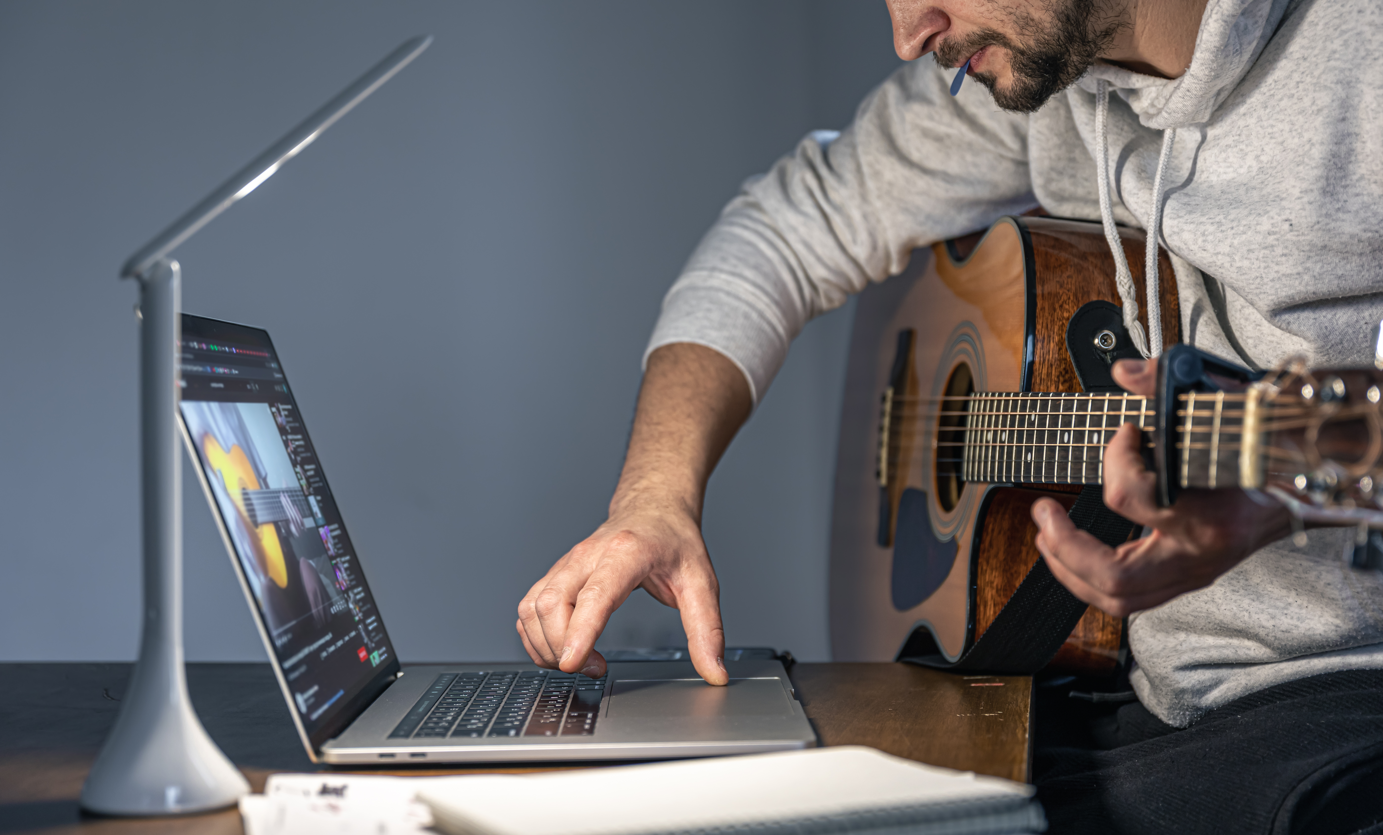 Docent geeft online gitaarles via een laptop