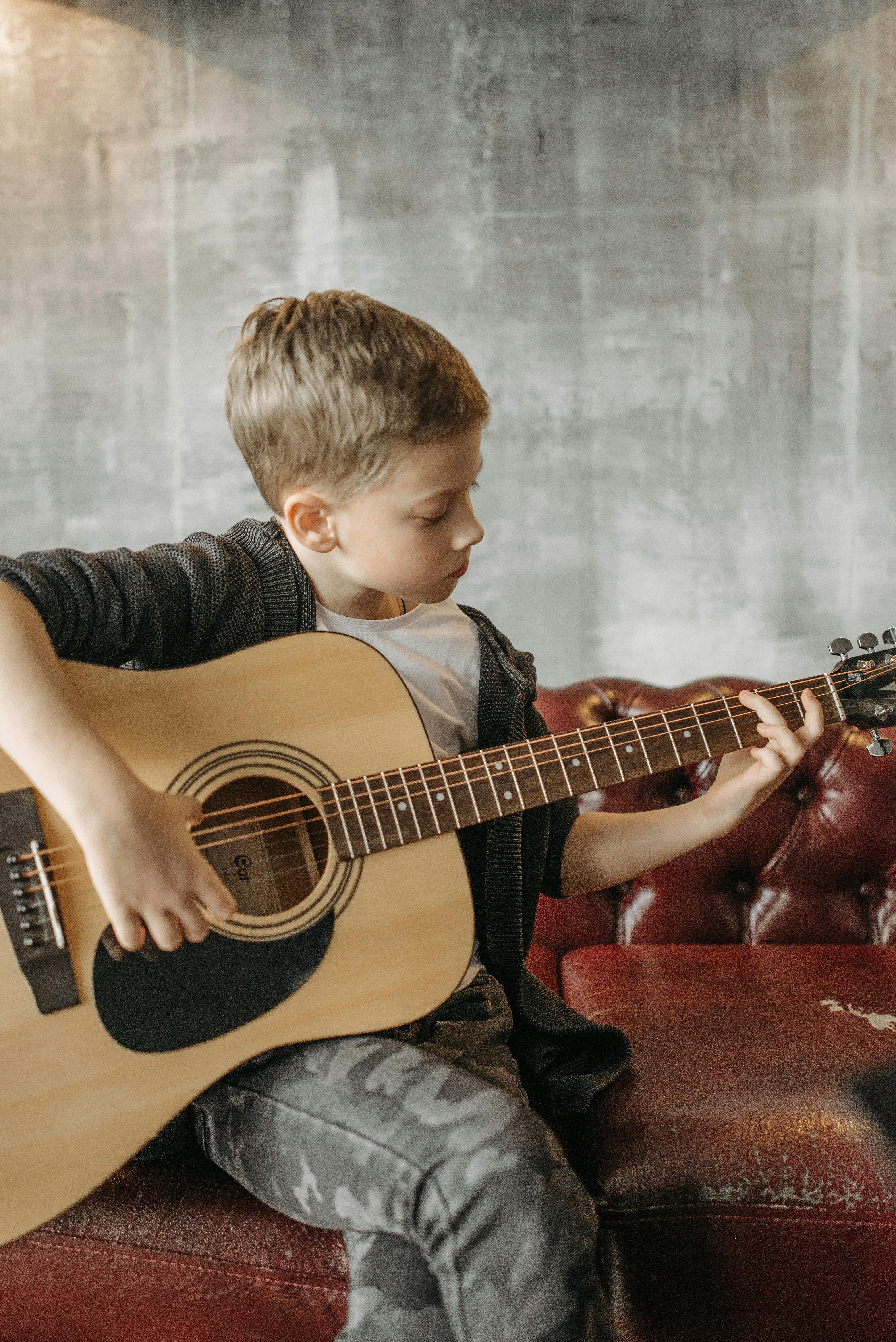 Kind leert gitaar spelen in les